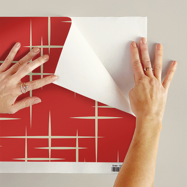The artwork consists of a red square background with a repeating pattern of starburst shapes created by intersecting elongated lines. These lines are light-colored, contrasting sharply against the red background. The lines form multiple four-pointed stars with varying lengths and thicknesses, radiating outward in a geometric arrangement. The composition presents a clean, mid-century modern aesthetic, emphasizing simplicity and bold contrasts.